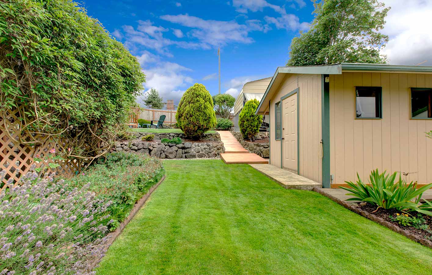 Fertiges Gartenhaus mit dekorativen Elementen und gepflegtem Garten.